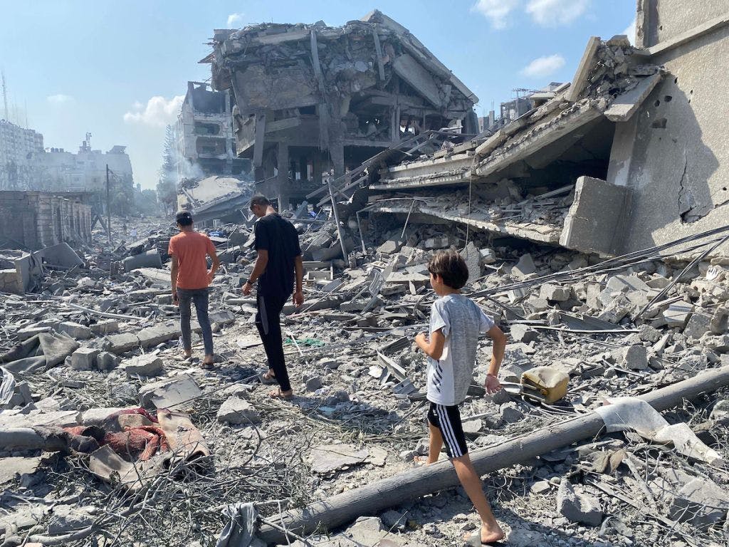 To barn og en voksen mann beveger seg gjennom ruiner i Gaza by